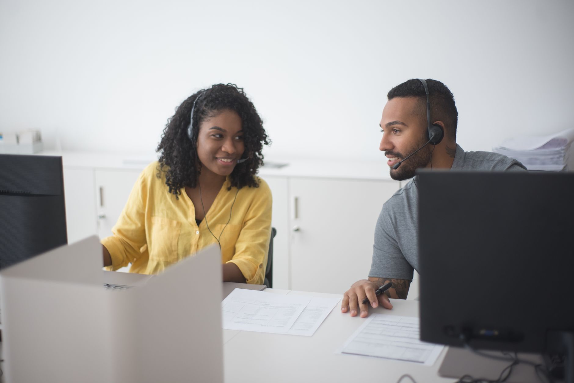 Two call center agents with headsets working together in a modern office, representing nearshore BPO customer service